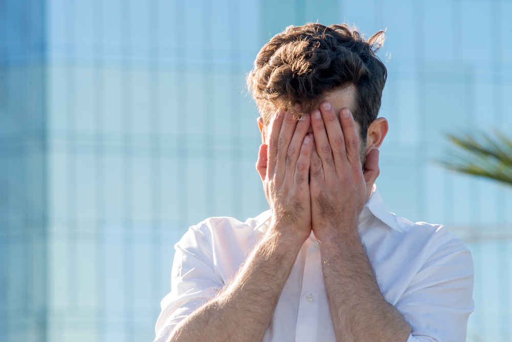 Young Man covered his face with his hands
